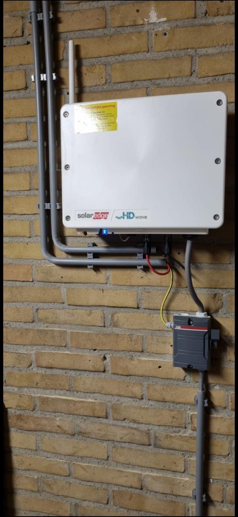 SolarEdge omvormer op bakstenen muur met kabelroute